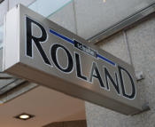 Roland, Leuchtkasten, Leuchtkästen, Leuchtreklame, Lichtwerbung, Leuchtwand, Fassandenleuchte, Dekupierter Kasten, LED Leuchtkasten, Werbekasten, Plexikasten, Nasenschild, Leuchtende Werbung, Reklame, Reklamewand, Leuchtreklame, Metallkasten, Geschäftsbes